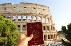 Hand holding Italian passport in front of Colosseum in Rome